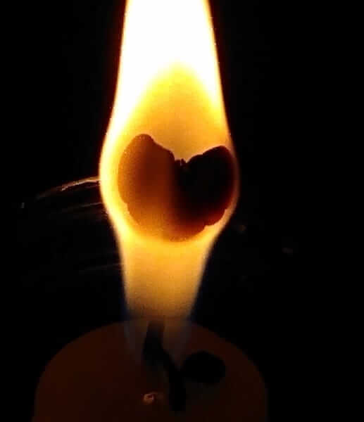 Lume di candela con un cuore in fiamme