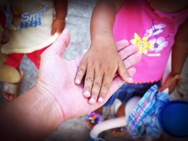 mano adulta si stringono la mano con una piccola bambina
