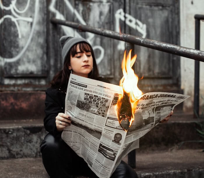 Ragazza che legge il giornale in fiamme