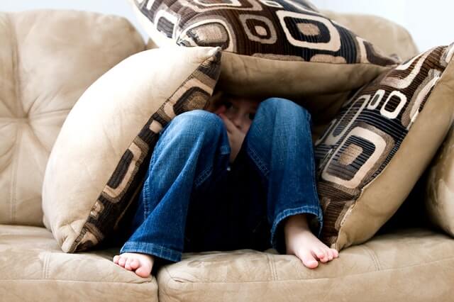 garota se escondendo sob almofadas